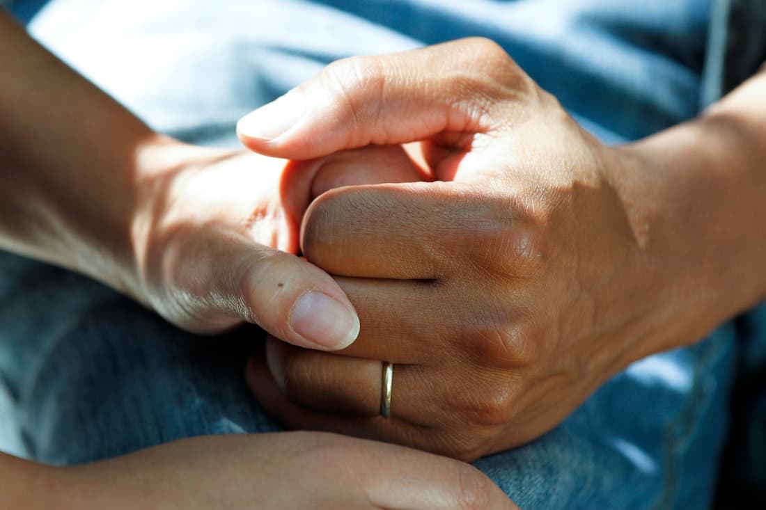 Healthcare professional holding a patient's hands in support